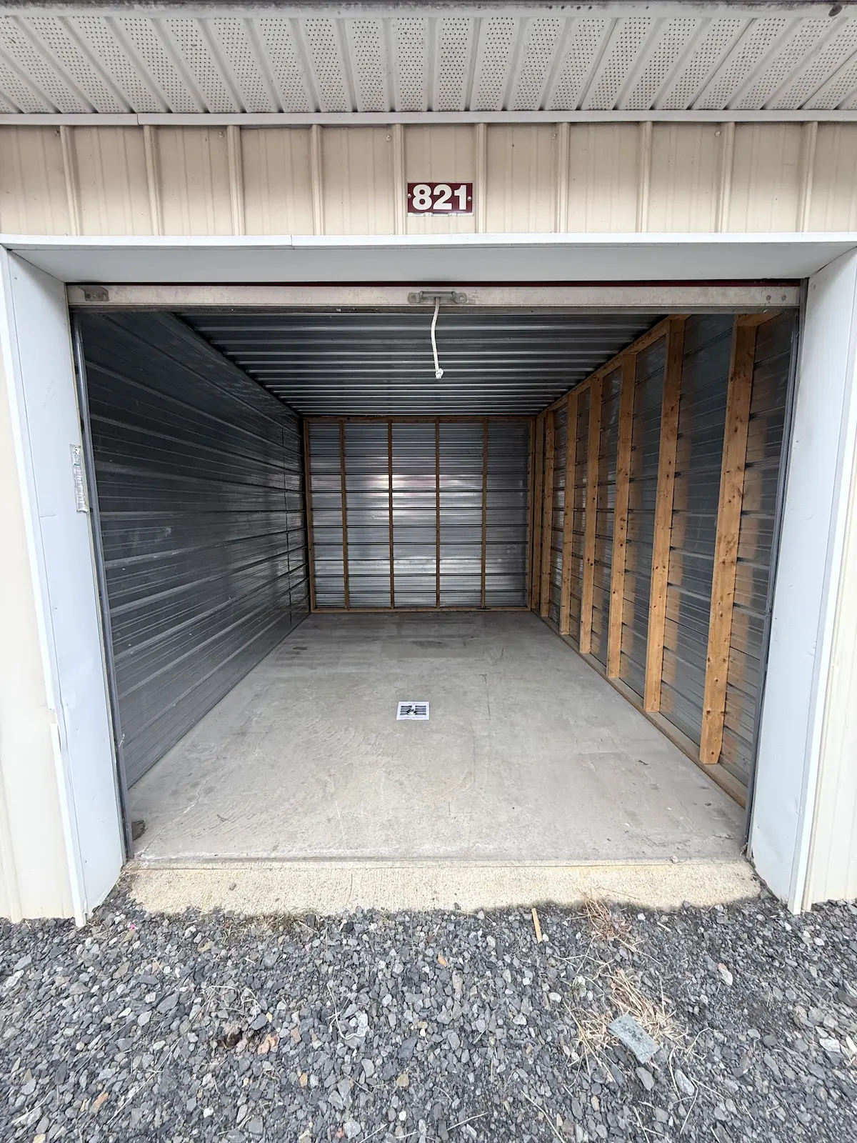 Interior of a 10x15 residential storage unit in Scranton with wooden shelving frame and horizontal metal storage slats, concrete floor, and clear space for personal items